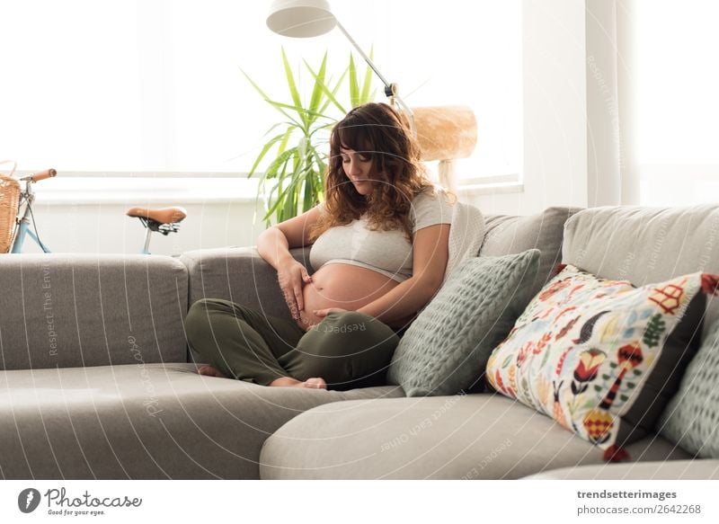 Schwangere Frau, die ihren Bauch berührt. Lifestyle Glück schön Leben Freizeit & Hobby Sofa Mensch Baby Erwachsene Eltern Mutter Familie & Verwandtschaft