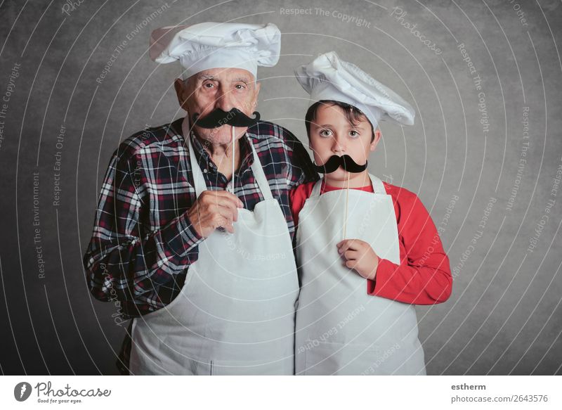 Großvater mit Enkel mit Koch Hut und Schnurrbart auf grauem Hintergrund Ernährung Diät Lifestyle Freude Freizeit & Hobby Küche Restaurant Feste & Feiern