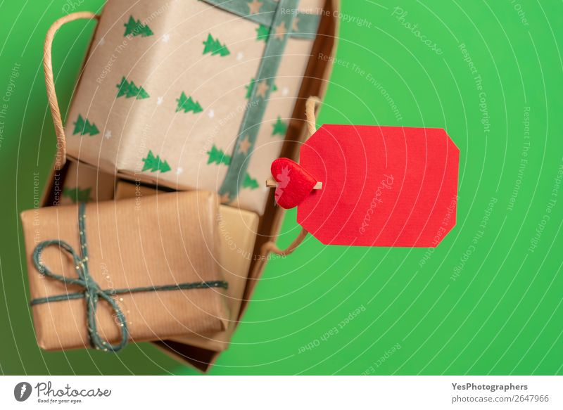 Leere Papiernotiz auf einer Tasche mit Weihnachtsgeschenken. Grüner Hintergrund Feste & Feiern Weihnachten & Advent Fröhlichkeit grün rot Überraschung Tradition