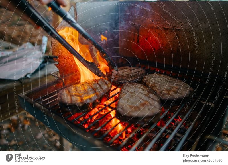 Vier Entrecôte / Rib-Eye-Steaks auf dem Grill mit hoher Flamme Lebensmittel Fleisch grillen Grillrost Grillsaison Ernährung Sommer Garten lecker bedrohlich
