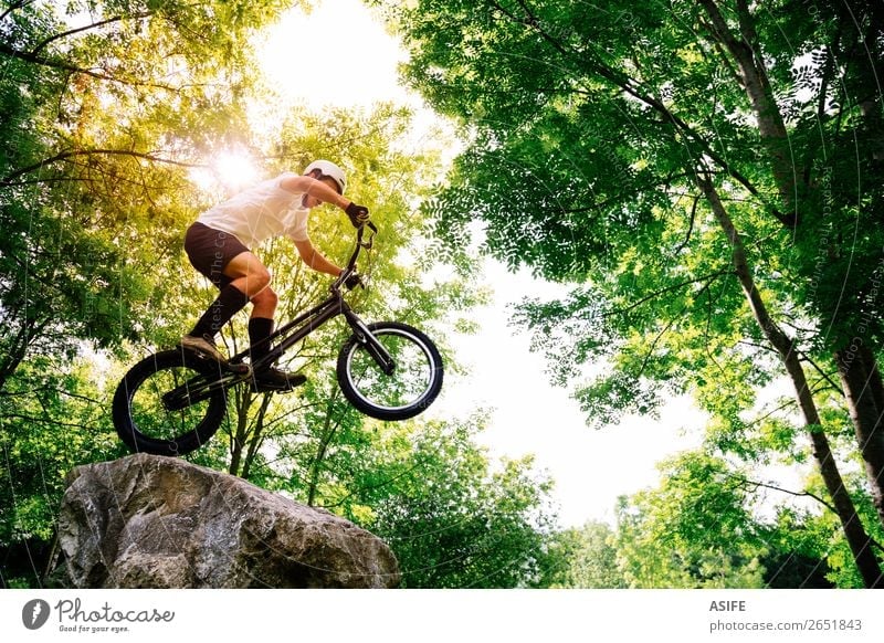 Junge Radfahrer, die Tricks in einem Felsen im Wald machen. Freiheit Sommer Berge u. Gebirge Sport Fahrradfahren Mann Erwachsene Natur Baum springen frei stark