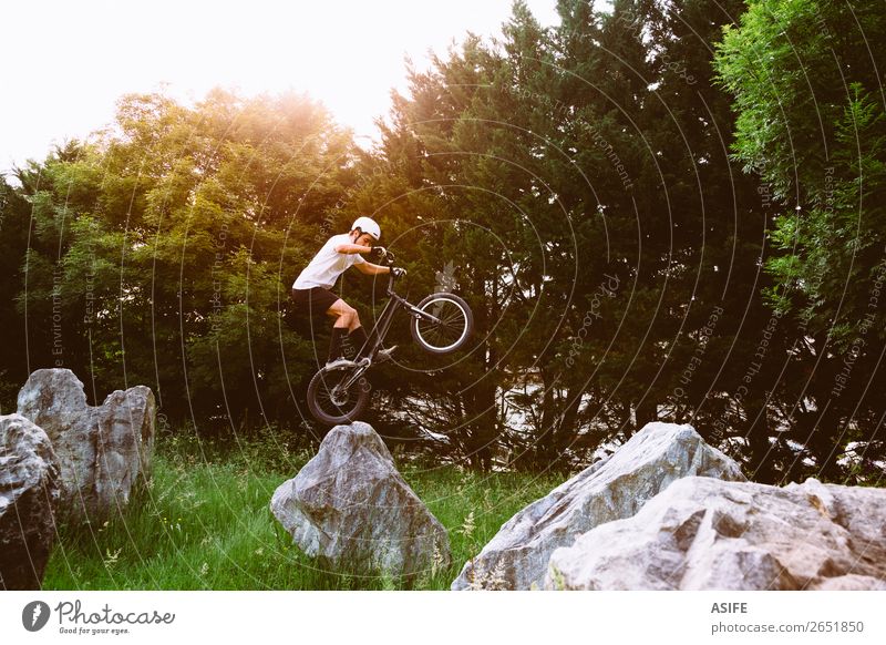 Junger Trial-Fahrradfahrer, der Tricks auf einem Felskurs macht. Freiheit Sommer Berge u. Gebirge Sport Fahrradfahren Mann Erwachsene Natur Baum Wald Felsen