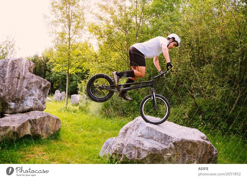 Junger Trial-Radfahrer, der in einem Felskurs Tricks macht. Freiheit Sommer Berge u. Gebirge Sport Fahrradfahren Mann Erwachsene Natur Baum Wald Felsen springen