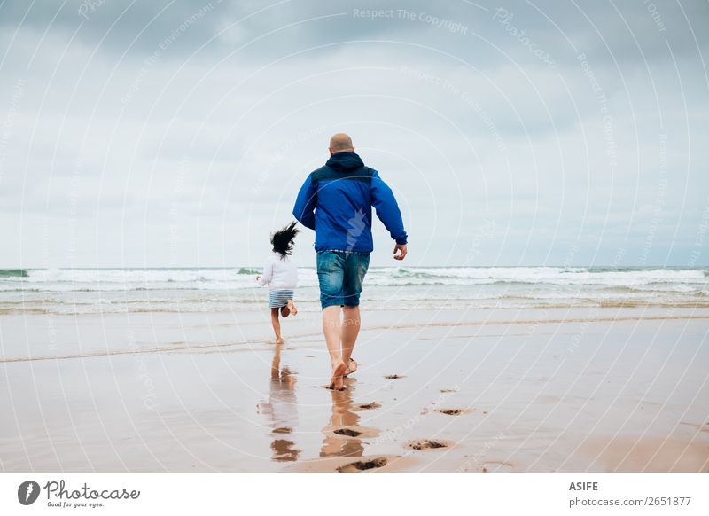 Vater und Tochter spielen am Strand an einem bewölkten Tag. Freude Glück Freizeit & Hobby Spielen Meer Kind Eltern Erwachsene Familie & Verwandtschaft Wolken
