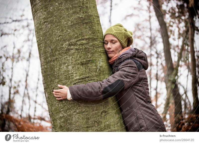 Frau mit Strickmütze und Mantel umarmt einen Baum, träumen in der Natur. harmonisch Wohlgefühl Sinnesorgane Erholung ruhig Meditation wandern Erwachsene Gesicht