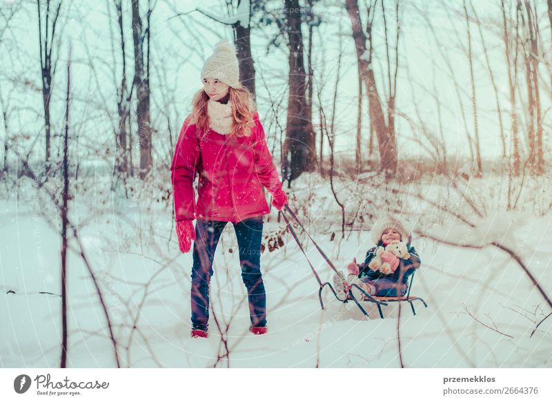 Teenagermädchen zieht mit ihrer kleinen Schwester Schlitten durch den Wald. Lifestyle Freude Glück Winter Schnee Winterurlaub Mensch Kind Baby Kleinkind Mädchen