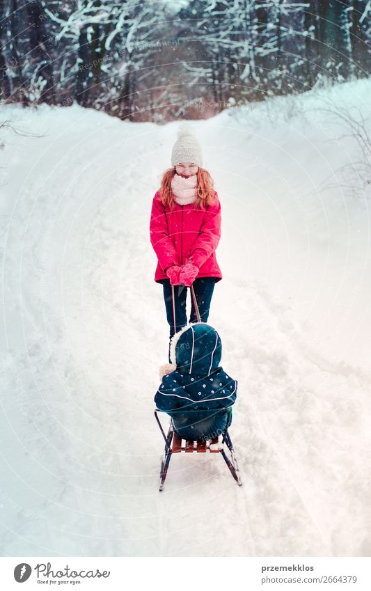 Teenagermädchen zieht mit ihrer kleinen Schwester Schlitten durch den Wald. Lifestyle Freude Glück Winter Schnee Winterurlaub Mensch Kind Mädchen Junge Frau