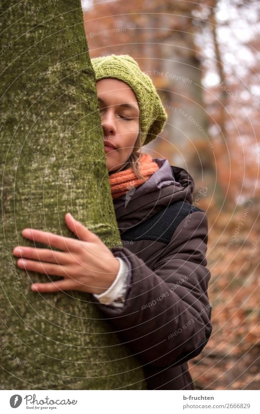 Frau mit Wollmütze, Schal und Wintermantel umarmt Baum Sinnesorgane Erholung ruhig Meditation Erwachsene Gesicht Hand Herbst Park Wald berühren stehen träumen