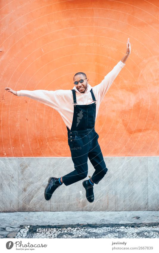 Junger schwarzer Mann in Freizeitkleidung springt im städtischen Hintergrund. Lifestyle Freude Glück schön Mensch maskulin Junger Mann Jugendliche Erwachsene 1