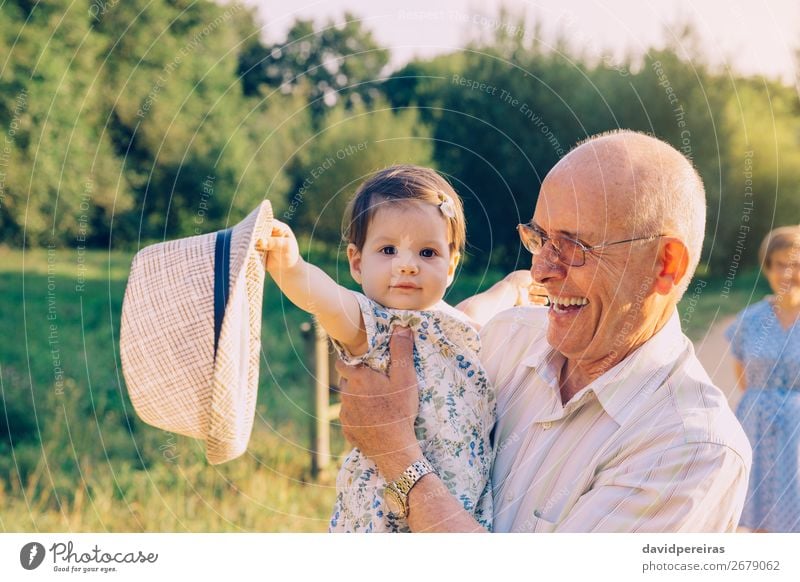 Baby-Mädchen spielt mit Hut des älteren Mannes über einen Natur-Hintergrund Lifestyle Glück Erholung Spielen Sommer Mensch Kleinkind Frau Erwachsene Eltern
