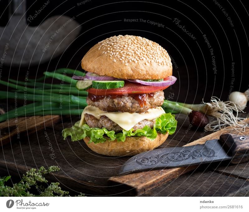 Cheeseburger mit Gemüse Fleisch Käse Brot Brötchen Mittagessen Abendessen Fastfood Messer Tisch Restaurant Holz dunkel frisch groß lecker grün schwarz