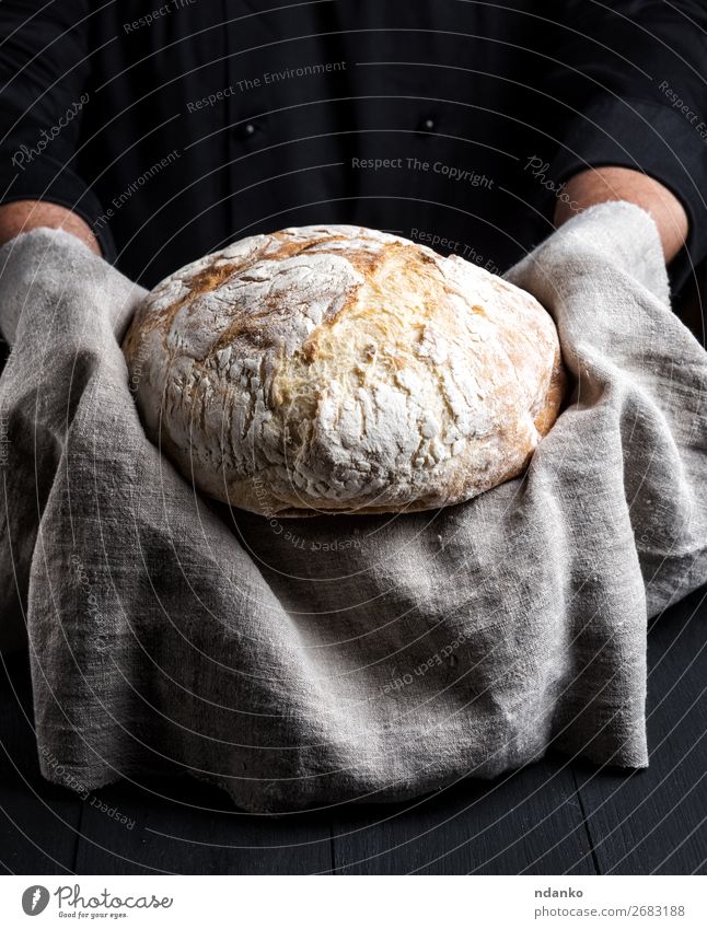 gebackenes rundes hausgemachtes Brot auf einer grauen Serviette Ernährung Tisch Küche Koch Mensch Hand Holz Essen machen dunkel frisch braun schwarz weiß
