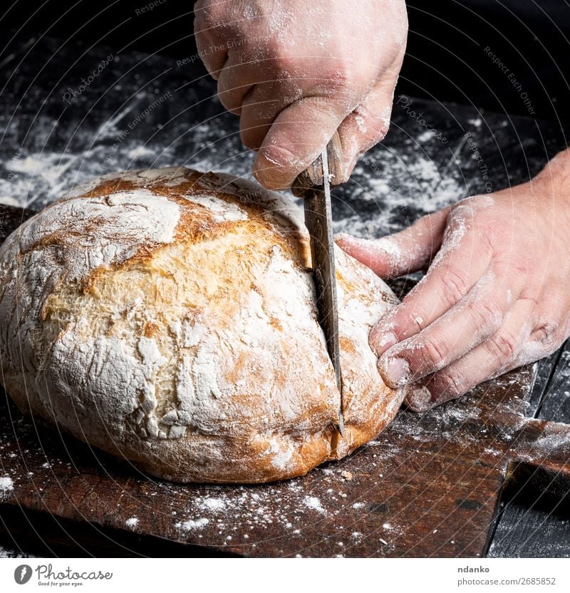 männliche Hände schneiden ein Messer rund gebackenes Brot Ernährung Tisch Küche Mensch Hand Finger Holz machen dunkel frisch braun schwarz weiß Tradition Bäcker