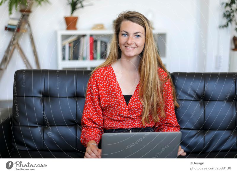 Lächelnde Frau, die zu Hause auf einem Sofa sitzt und einen Laptop benutzt. kaufen Glück schön Schule lernen Studium Arbeit & Erwerbstätigkeit Computer Notebook