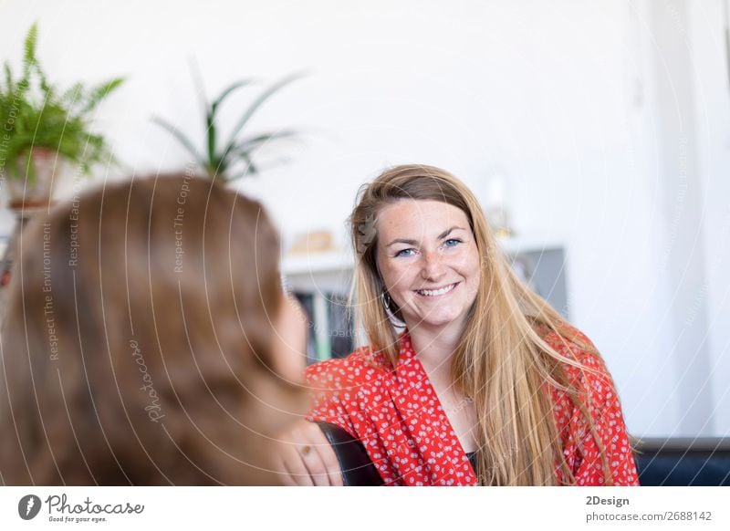 Zwei Freunde unterhalten sich lachend auf einem Sofa im heimischen Wohnzimmer schön Windstille Wohnung Sitzung sprechen Mensch feminin Junge Frau Jugendliche