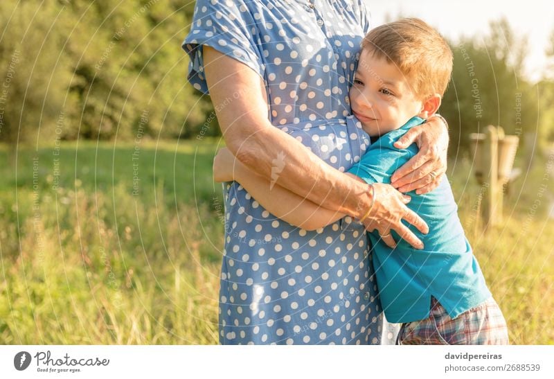 Glücklicher Enkel, der seine Großmutter im Freien umarmt. Lifestyle Erholung Freizeit & Hobby Sommer Garten Kind Mensch Junge Frau Erwachsene Mann Eltern