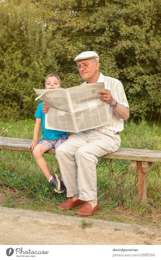Senior Mann und gelangweiltes Kind lesen Zeitung im Freien Lifestyle Glück Erholung Freizeit & Hobby Schule Mensch Junge Erwachsene Eltern Großvater