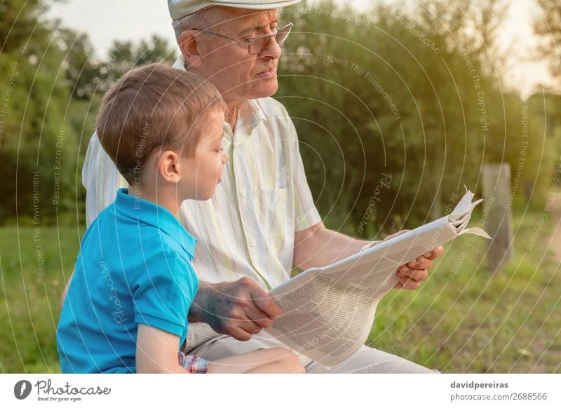 Senior Mann und Kind lesen eine Zeitung im Freien. Lifestyle Glück Erholung Freizeit & Hobby Schule Mensch Junge Erwachsene Eltern Großvater