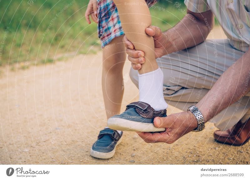 Großvater legt seinem Enkel den Schuh im Freien an. Lifestyle Freizeit & Hobby Sommer Garten Kind Mensch Junge Mann Erwachsene Eltern Familie & Verwandtschaft