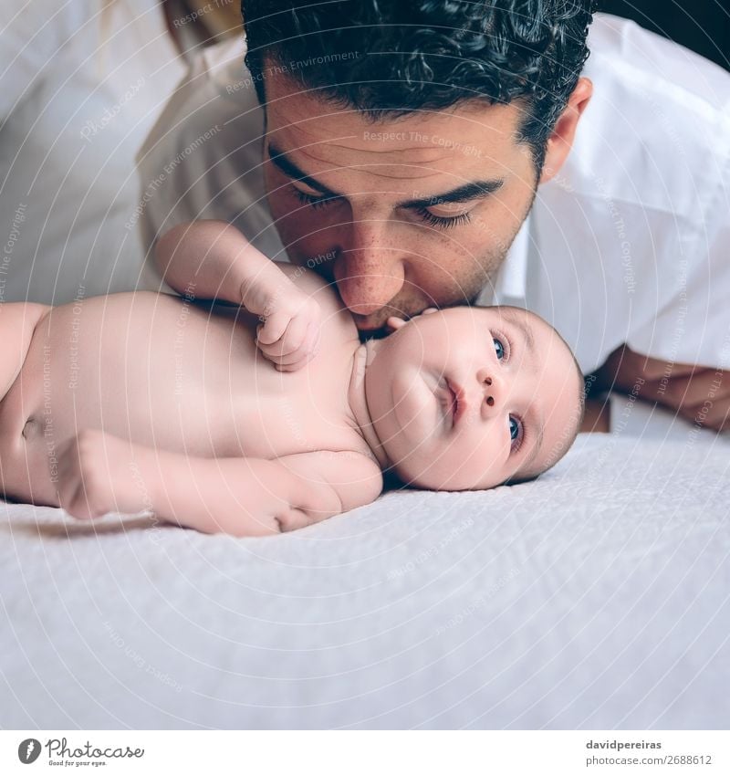 Mann küssend an friedliches Neugeborenes, das über dem Bett liegt. Lifestyle Freude Glück schön Freizeit & Hobby Schlafzimmer Kind Mensch Baby Kleinkind Junge