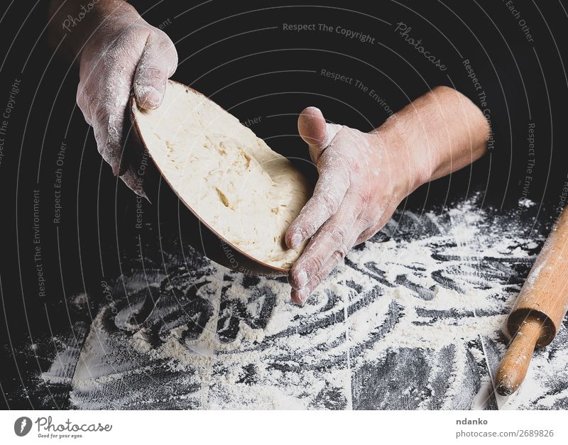 männliche Hand, die eine Keramikplatte mit Hefeteig hält. Teigwaren Backwaren Brot Ernährung Teller Tisch Küche Koch Mann Erwachsene Holz machen frisch schwarz