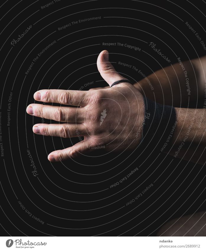 Der Mann wickelt seine Hände in eine schwarze Textilbinde. Lifestyle Haut Fitness Sport Mensch Erwachsene Arme Hand 1 30-45 Jahre drehen Aggression dunkel stark