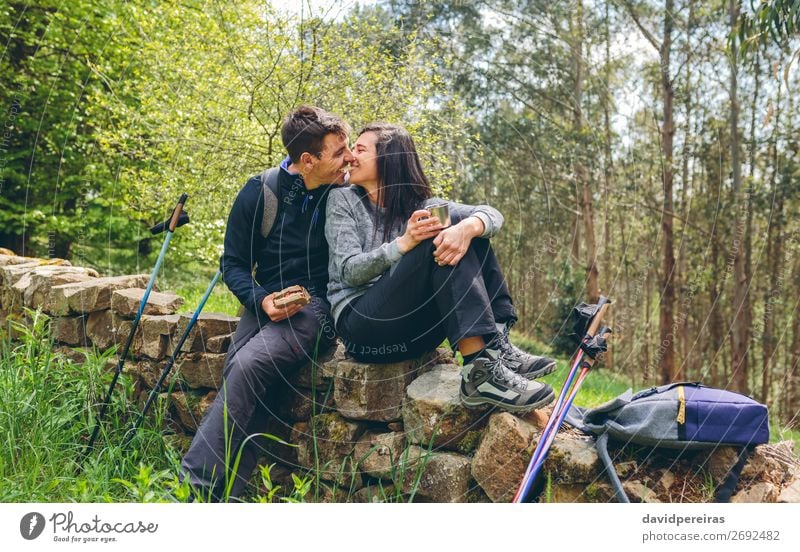 Ein Paar, das sich küssen will, während es eine Pause macht, um Trekking zu machen. Essen trinken Lifestyle Freizeit & Hobby Abenteuer Berge u. Gebirge wandern
