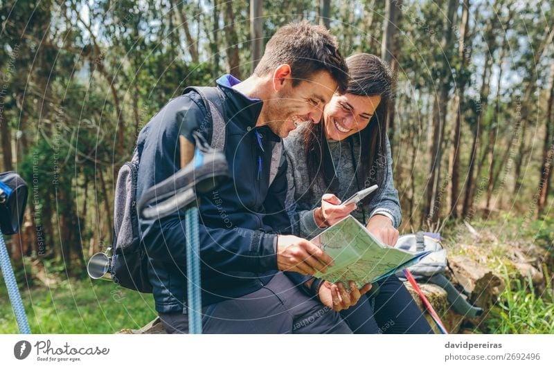 Ein Paar beim Trekking im Sitzen, das mobil aussieht und eine Karte hat. Freude Glück Ausflug Abenteuer Sightseeing Berge u. Gebirge wandern Sport PDA Mensch