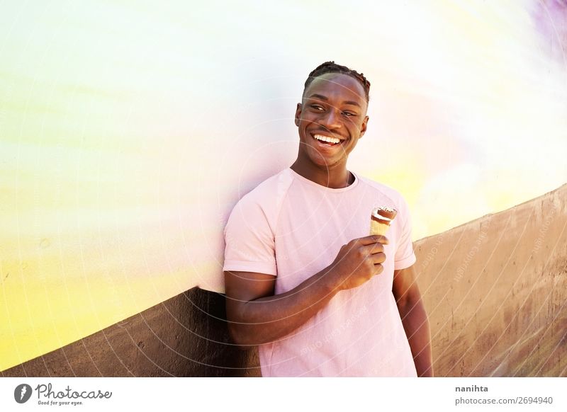 Ein junger, gutaussehender schwarzer Mann hält ein Eis. Lebensmittel Speiseeis Essen Lifestyle Stil Glück Wellness Sommer Sonnenbad Mensch maskulin Junger Mann