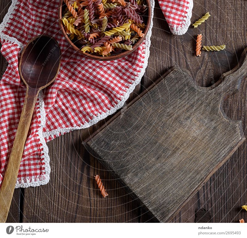 rohe Nudelnusilli auf einem braunen Holztisch Teigwaren Backwaren Ernährung Italienische Küche Schalen & Schüsseln Löffel Tisch retro gelb rot Farbe Tradition