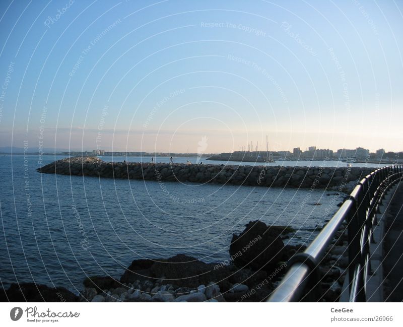 Blick zur Hafenmauer Mauer Anlegestelle Licht Belichtung Dämmerung Meer Spanien Wasser Stein Bruchstück Felsen Sonne Estartit Himmel blau Geländer Metall Bucht
