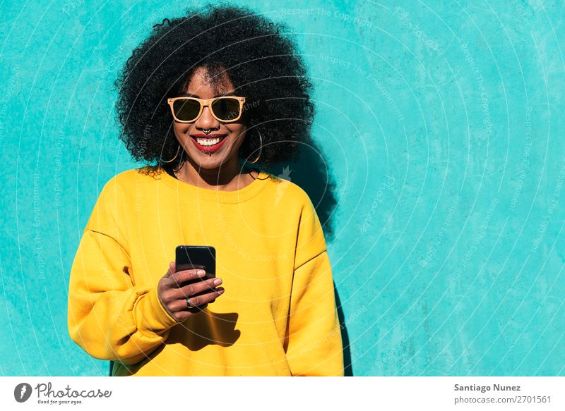 Schöne afroamerikanische Frau, die ein Handy auf der Straße benutzt. schwarz Afrikanisch Afro-Look Mensch Porträt PDA Jugendliche Mobile Telefon Mädchen