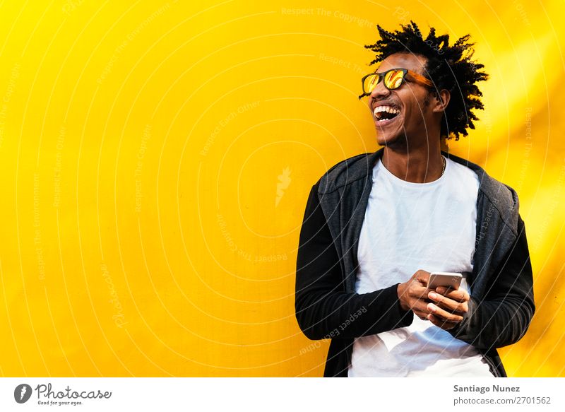Porträt eines gutaussehenden Afro-Mannes mit seinem Handy. Mobile Glück Lächeln Afro-Look schwarz Afrikanisch Mulatte Telefon Schickimicki Lifestyle stehen