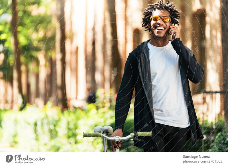 Afro-Jugendlicher benutzt Mobiltelefon und Fahrrad mit fester Gangschaltung Mann Afrikanisch schwarz Lifestyle attraktiv gutaussehend jung urban modern