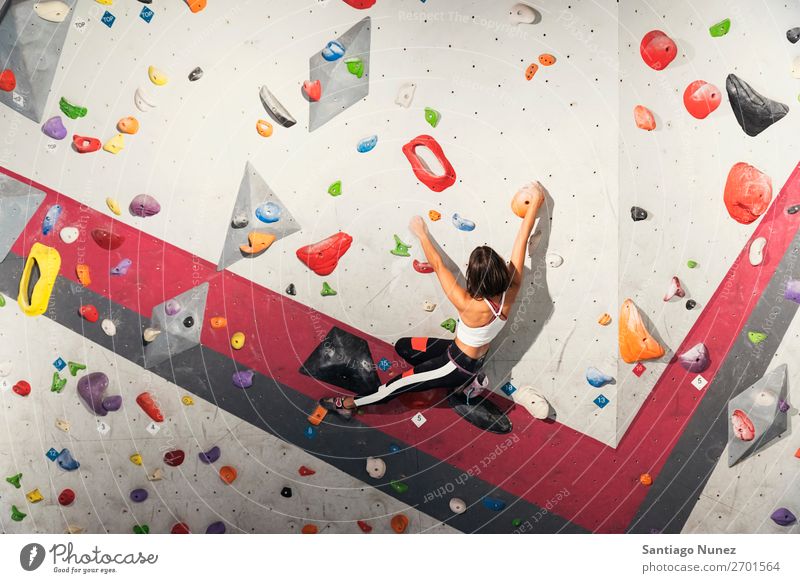 Frau, die das Klettern an einer künstlichen Wand in Innenräumen übt. Aufsteiger Felsen im Innenbereich Sporthalle Jugendliche Fitness Freizeit & Hobby Aktion