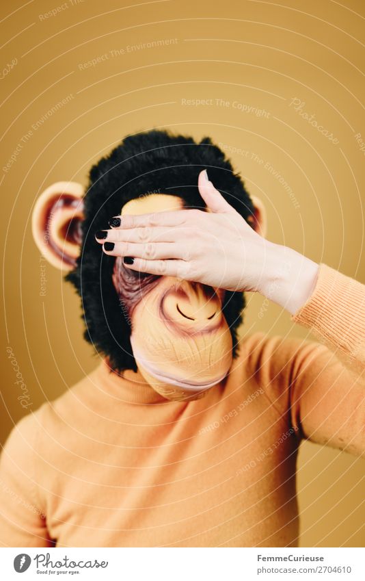 Woman with monkey mask holding her hand in front of her face feminin Frau Erwachsene 1 Mensch 18-30 Jahre Jugendliche 30-45 Jahre gelb Affen Schimpansen