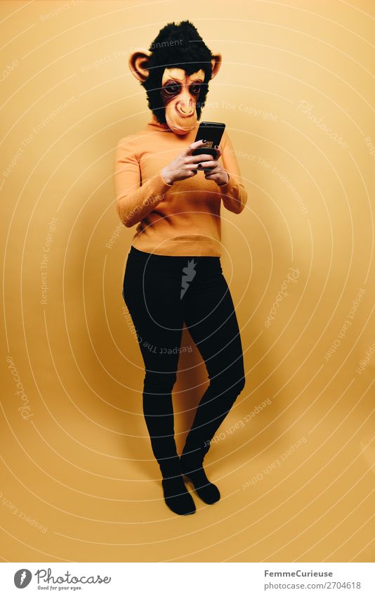Woman with monkey mask looking at her smartphone Technik & Technologie Unterhaltungselektronik feminin Frau Erwachsene 1 Mensch 18-30 Jahre Jugendliche