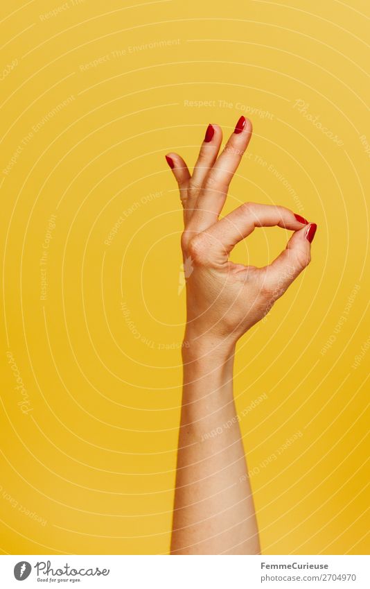 Hand signal for okay against a yellow background feminin Frau Erwachsene 1 Mensch 18-30 Jahre Jugendliche 30-45 Jahre Kommunizieren Zeichen gestikulieren