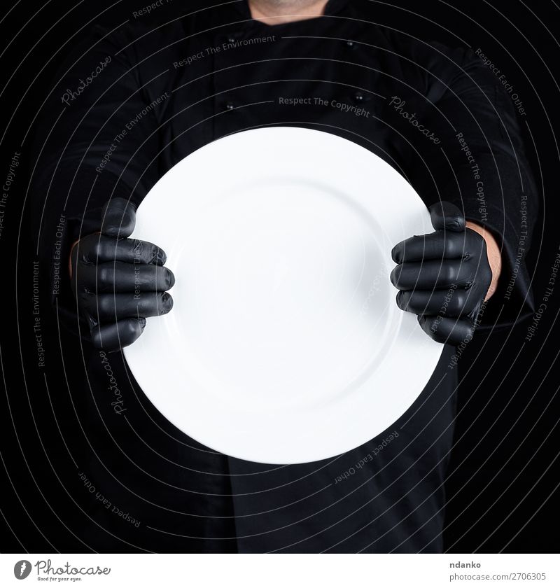Koch in schwarzer Uniform mit einem runden leeren Teller. Küche Restaurant Beruf Mensch Mann Erwachsene Hand Handschuhe dunkel weiß Küchenchef Halt Lebensmittel