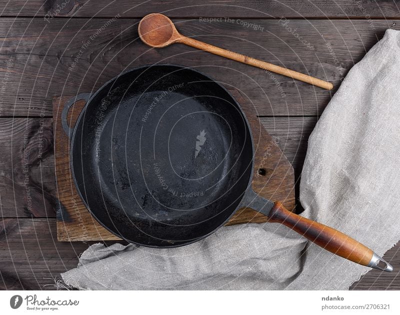 leere schwarze runde Pfanne mit Holzgriff Abendessen Löffel Tisch Küche Metall alt dunkel oben Sauberkeit braten Hintergrund bügeln gießen Aussicht Top