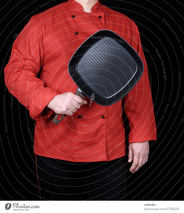 in roter Uniform kochen und eine leere quadratische schwarze Bratpfanne halten. Pfanne Küche Restaurant Beruf Koch Mensch Hand einreihiger Mantel Grillrost