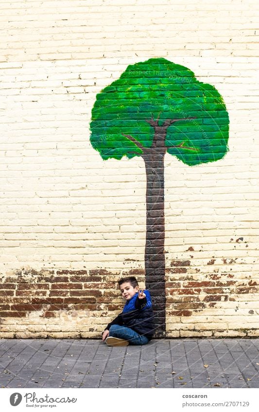 Kleines Kind, das unter einem Baum sitzt, der an einer Wand gemalt ist. Lifestyle Design Freude Glück schön Spielen Ferien & Urlaub & Reisen Abenteuer Winter