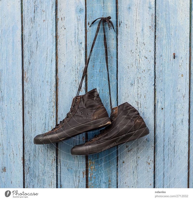 Paar schwarze Textilsneakers Lifestyle Stil Sport Joggen Mode Bekleidung Schuhe Turnschuh Holz alt hängen dreckig modern retro blau Hintergrund Holzplatte