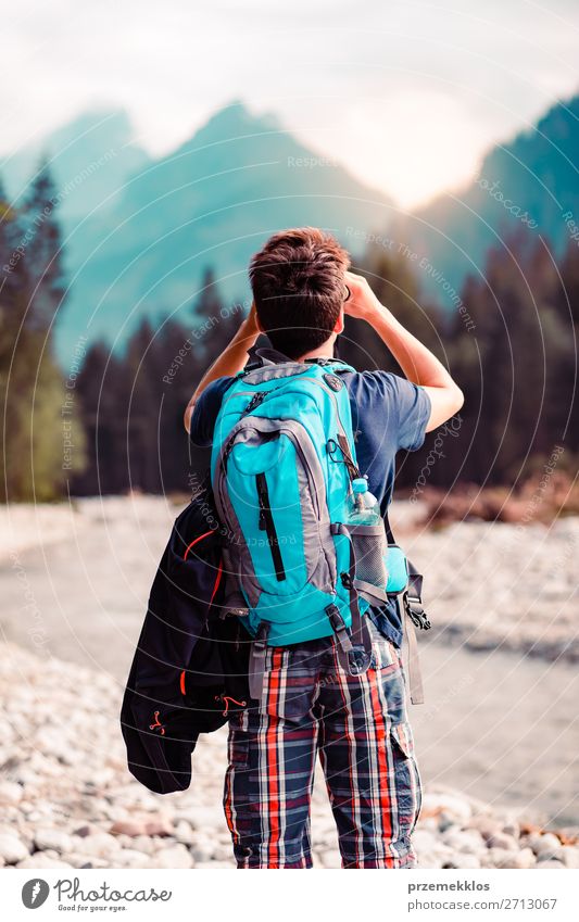 Junger Wanderer mit Rucksack schaut durch ein Fernglas. Lifestyle Leben Freizeit & Hobby Ferien & Urlaub & Reisen Tourismus Ausflug Abenteuer Sommer
