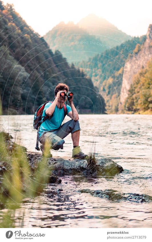 Junger Tourist mit Rucksack schaut durch ein Fernglas. Lifestyle Leben Freizeit & Hobby Ferien & Urlaub & Reisen Ausflug Sommer Berge u. Gebirge Mensch