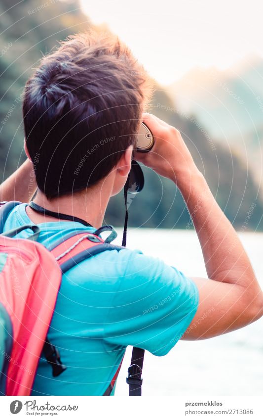 Junger Tourist mit Rucksack schaut durch ein Fernglas. Lifestyle Leben Freizeit & Hobby Ferien & Urlaub & Reisen Ausflug Sommer Berge u. Gebirge Mensch
