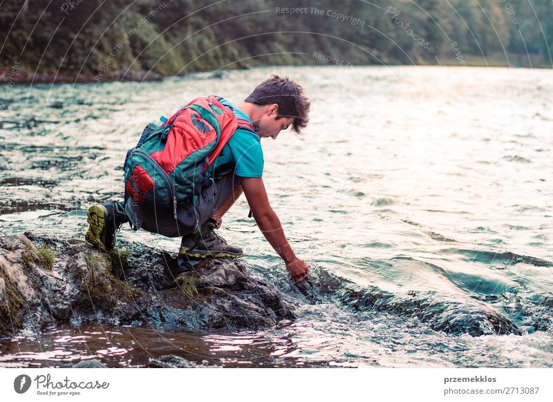 Kleiner Junge mit Rucksack, der auf einem Felsen über einem Fluss sitzt. Lifestyle Körper Leben Freizeit & Hobby Ferien & Urlaub & Reisen Ausflug Sommer Mensch