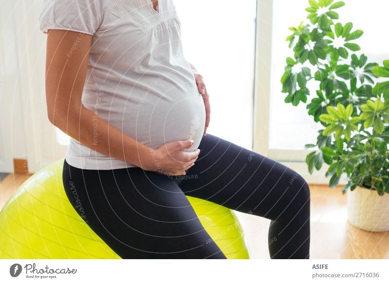 Schwangere Frau beim Training zu Hause Glück Körper Sport Baby Erwachsene Eltern Mutter Hand berühren Fitness sitzen schwanger grün Zukunft Schwangerschaft üben