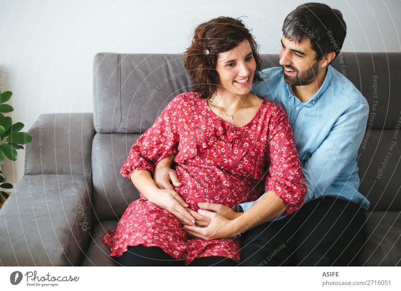 Glückliches schwangeres Paar auf dem Sofa schön Körper Baby Frau Erwachsene Mann Eltern Mutter Vater Familie & Verwandtschaft Blume Kleid berühren Lächeln Liebe