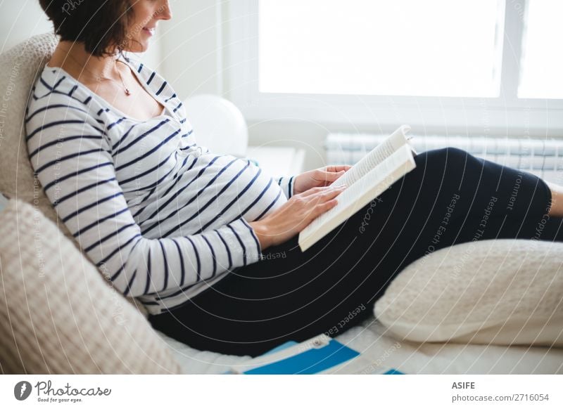 Schwangere Frau beim Lesen eines Schwangerschaftsbuchs auf dem Bett Glück schön Körper Erholung Freizeit & Hobby lesen Schlafzimmer Baby Erwachsene Eltern